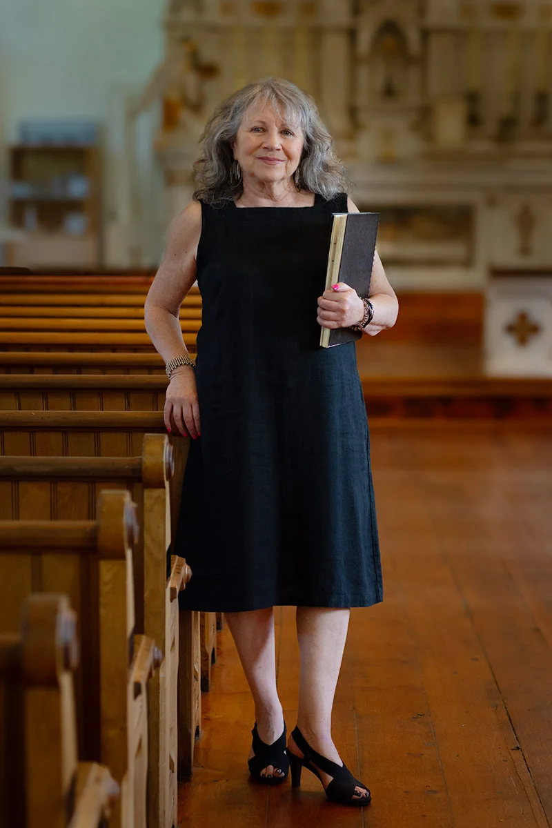 Caroline Kohn standing in Église historique de Barachois, Grand Barachois, NB, before one of her Lecture and Q&A Series.